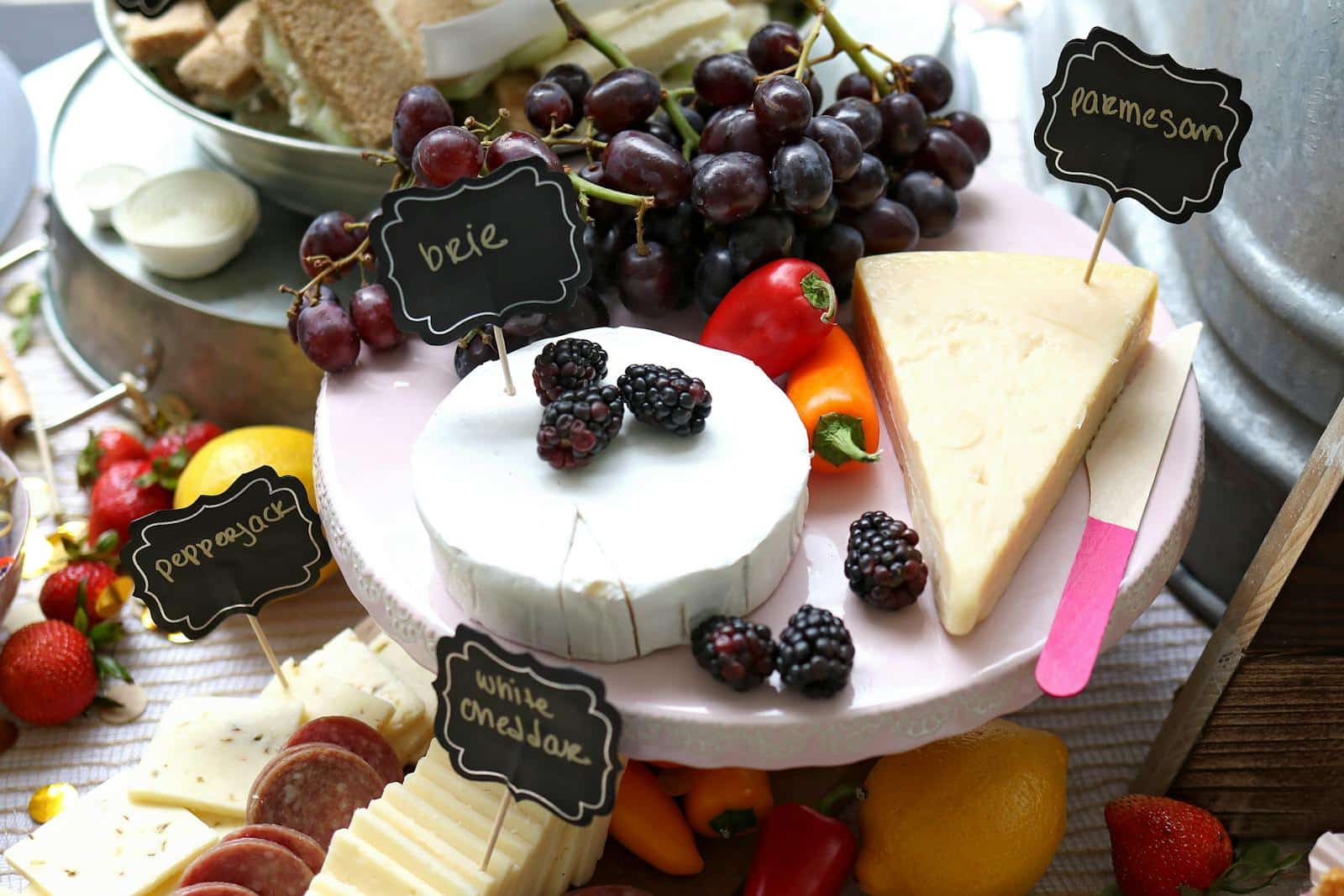 A vibrant cheese platter featuring brie, parmesan, fresh fruits, and vegetables.