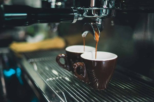 Close-up of a professional espresso machine brewing coffee into cups.