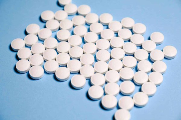 Close-up of white pills on a blue surface representing healthcare and medication.