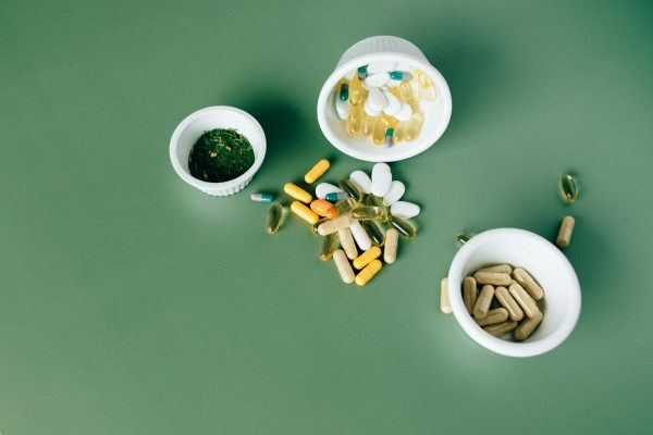 Various herbal and vitamin pills and capsules on a green surface. Probiotics